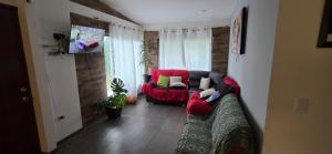 a living room with a red couch and a chair at "Refugio campestre familiar - Cálido, cómodo y totalmente equipado" y zona de juegos in Nariño