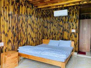a bed in a room with a bamboo wall at Bon Ben Homestay in Hòa Bình