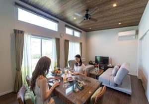 two women sitting at a table in a living room at BEVERLY HILLS VILLA Miyakojima Resort in Miyako-jima