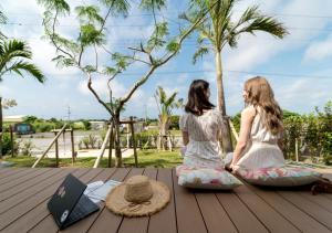 two young girls sitting on a deck with a book at BEVERLY HILLS VILLA Miyakojima Resort in Miyako-jima