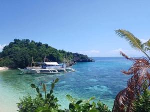 a boat in the water next to a beach at MANEL Guest House - Donsol, Philippines in Donsol