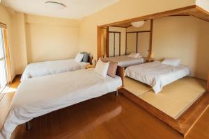 a bedroom with three beds and a mirror at 愛犬と休日を過ごすサウナハウス-COZY HOUSE Izukogen- in Ito
