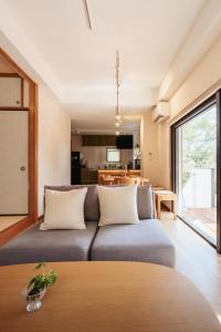 a living room with a couch and a kitchen at 愛犬と休日を過ごすサウナハウス-COZY HOUSE Izukogen- in Ito