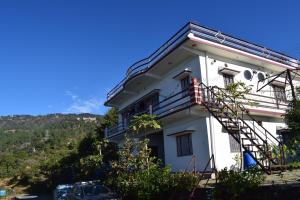 a white house with a staircase on the side of it at Rameshwari Homestay in Lansdowne