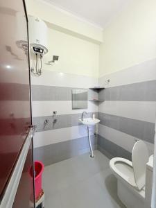 a bathroom with a white toilet and a sink at Rameshwari Homestay in Lansdowne