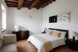 a white bedroom with a bed and a chair at VILLA ADELE - Ville Carborello in Crispiero