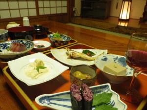 a table with plates of food and a glass of wine at Hagurokan in Tsuruoka