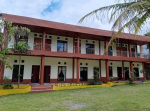 a building with a palm tree in front of it at Askara Toba Cottage in Tuktuk Siadong