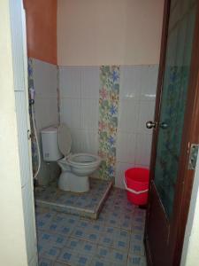 a bathroom with a toilet and a red bucket at Askara Toba Cottage in Tuktuk Siadong