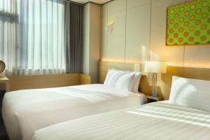 a hotel room with two beds and a window at Orakai Cheonggyesan Hotel, BW Premier Collection in Seoul