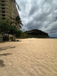 a sandy beach with a palm tree and a mountain at 305 On the Beach in Waianae +9 photos