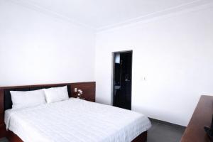 a bedroom with a white bed and a black door at Thành Trung Hotel Nghệ An in Vinh
