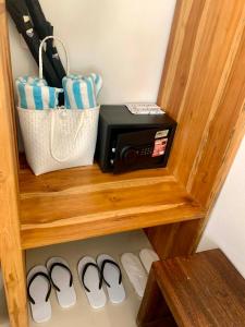 a wooden shelf with a microwave and two pairs of shoes at Andaman Beach Resort by Zodiac in Ko Lipe
