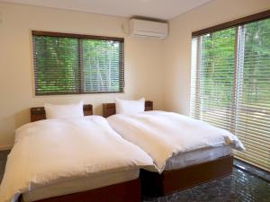 a bedroom with two beds and two large windows at A-PLAZA Yamanakako in Yamanakako