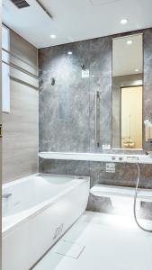 a bathroom with a tub and a sink and a mirror at 9Stay市原 in Ichihara