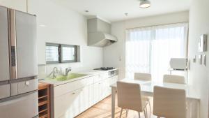 a kitchen with white cabinets and a kitchen table with chairs at 9Stay市原 in Ichihara +80 photos