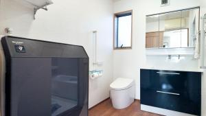 a bathroom with a toilet and a black refrigerator at 9Stay市原 in Ichihara
