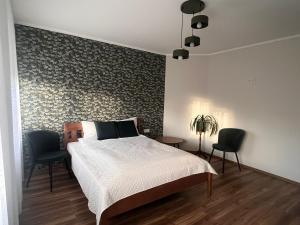 a bedroom with a bed and two chairs at Viduma apartamenti in Ventspils