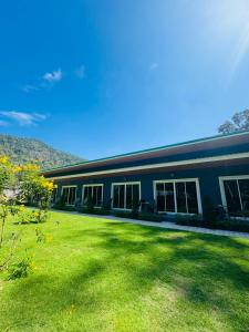 a building with a grass yard in front of it at Blue Mountain Kamala Phuket in Kamala Beach