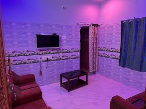 a purple room with a tv and two chairs and a table at Jacobs Cottage KG-F1 in Thiruchendur