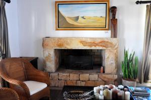 a living room with a fireplace with a painting on the wall at Draaihoek Lodge & Restaurant in Elands Bay