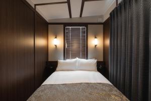 a bedroom with a bed with white pillows and a window at JR Mobile Inn Hakodate in Hakodate