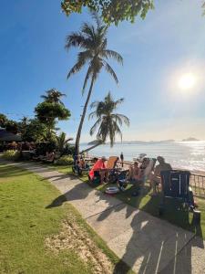 a group of people sitting on the grass near the beach at Doublegem Beach Resort and Hotel in El Nido
