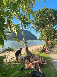 a group of people laying on the grass at the beach at Doublegem Beach Resort and Hotel in El Nido