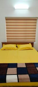 a bedroom with a bed with yellow pillows at Ivory Suites Meadows in Kozhikode