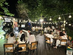 a group of people sitting at tables at a restaurant at night at The SkyView Villa & Resort in Kệ Sơn +104 photos