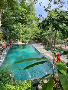 a pool of blue water in the middle of a forest at The SkyView Villa & Resort in Kệ Sơn