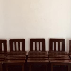 a row of wooden chairs in a room with a wall at Hotel Ashoka Kokan Ganpatipule in Ganpatipule +54 photos