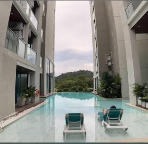 a man laying on two chairs in a swimming pool at patong see view condo in Patong Beach