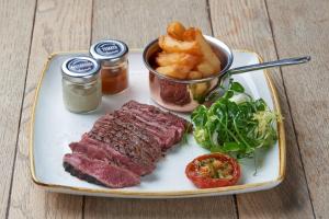 um prato com bife e batatas fritas e uma tigela de anéis de cebola em The Corner House Canterbury em Canterbury