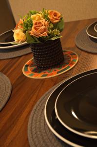 a vase of orange roses on a table with plates at Cesar's Apartment - Los Laureles in Lima
