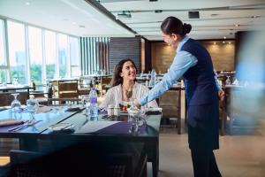 a woman standing over a table in a restaurant at Flora Creek Deluxe Hotel Apartments, Dubai in Dubai +53 photos