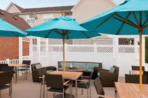 a patio with tables and chairs with blue umbrellas at PrimeStay Extended Suites by IHG in Madison