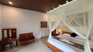 a bedroom with a canopy bed with a chair and a desk at Abian view house in Sidemen