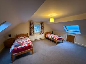 a attic bedroom with two beds and two windows at 4 Bedroom House By Travel Lets Holiday Homes Downings With Beautiful Ocean View in Downings