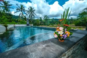 a swimming pool with flowers on a retaining wall at Arsyana Villa in Sidemen