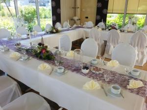 una mesa larga con sillas blancas y mesas blancas con flores en Business Vital Hotel am Rennsteig en Suhl