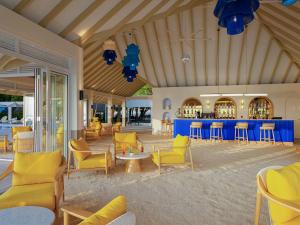 a lobby with yellow chairs and a bar at Eri Maldives in North Male Atoll