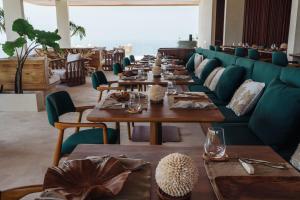 a long dining room with wooden tables and green couches at Vanara Resort and Spa in Uluwatu