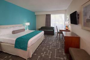 ein Hotelzimmer mit einem großen Bett und einem Stuhl in der Unterkunft Howard Johnson by Wyndham Toms River in Toms River