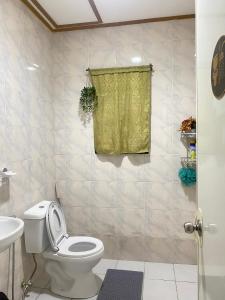 a bathroom with a toilet and a yellow shower curtain at Naybe's Room rentals in Dapa +4 photos