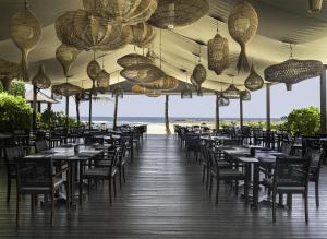 a restaurant with tables and chairs on the beach at The Apurva Kempinski Bali in Nusa Dua