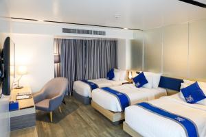 a hotel room with two beds and a chair at Wintree City Resort Chiang Mai in Chiang Mai +32 photos