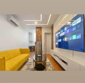 a living room with a yellow couch and a large tv at Home helpers in Lagos