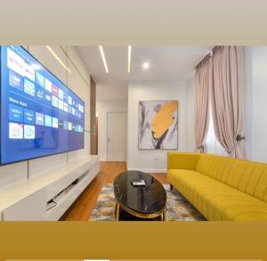 a living room with a yellow couch and a large tv at Home helpers in Lagos +2 photos