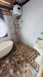 a bathroom with a mosaic floor with a toilet and a sink at Villa Lakdu in Sorongjukung
